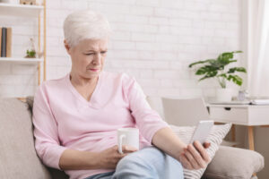 older woman sitting on couch and using cell phone 