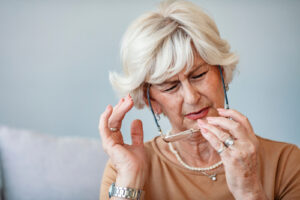 older woman taking eyeglasses off 