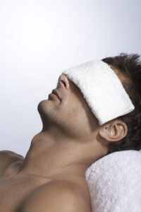 man with a massage towel across his eyes