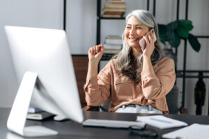 woman at her desk smiling during a phone call