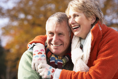 A smiling older couple embrace while looking off-camera