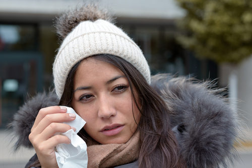 A woman holding a tissue near her eyes