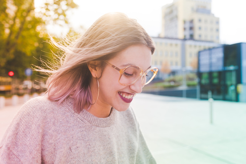 woman smiling on a walk while wearing sweater and glasses